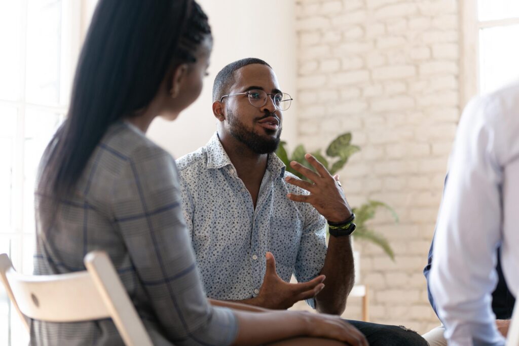 Man speaking in a group session while others listen